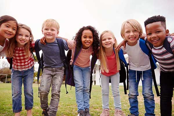 A group of young people standing on a field with their arms around each other.