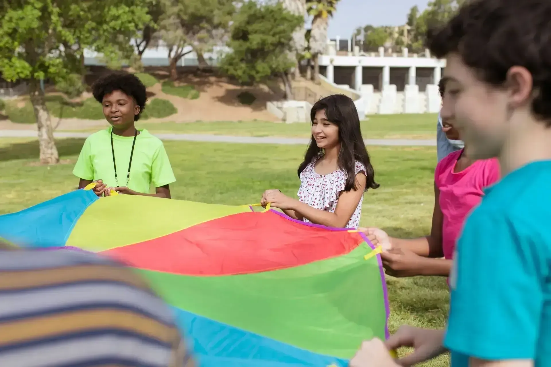 A group of young people standing on a field holding a colorful flag.