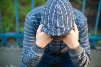 Sad Teenage Student in a Hoodie covering his face