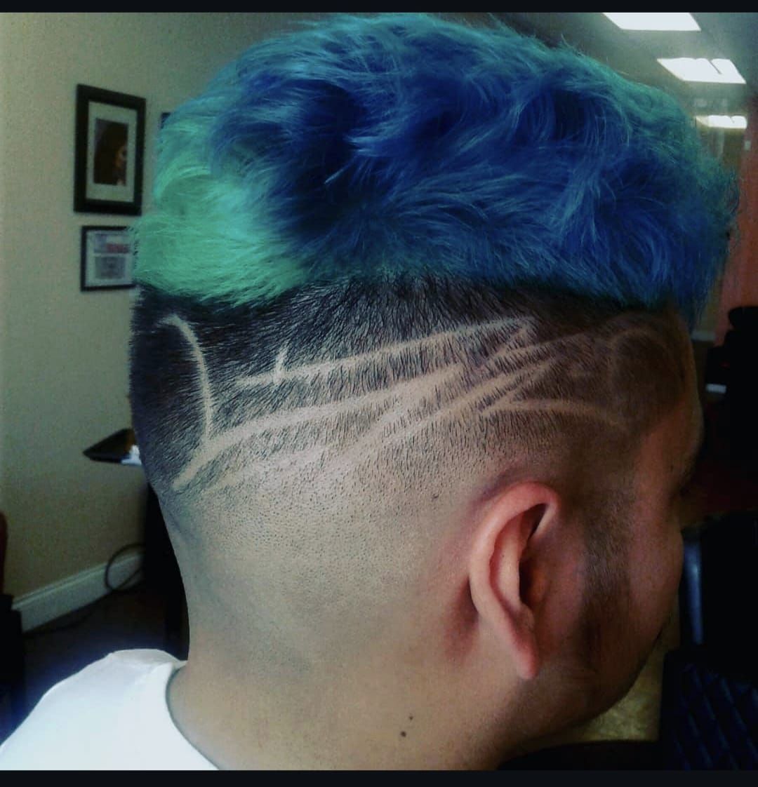 Side view of a blue-green dyed mohawk with shaved, patterned fade haircut