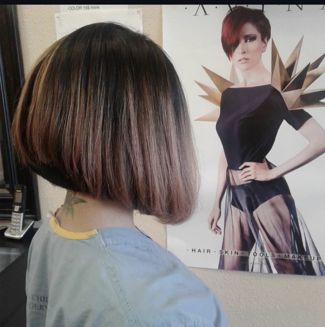 Side view of a short brown bob haircut in a salon, with a hairstyle poster in the background