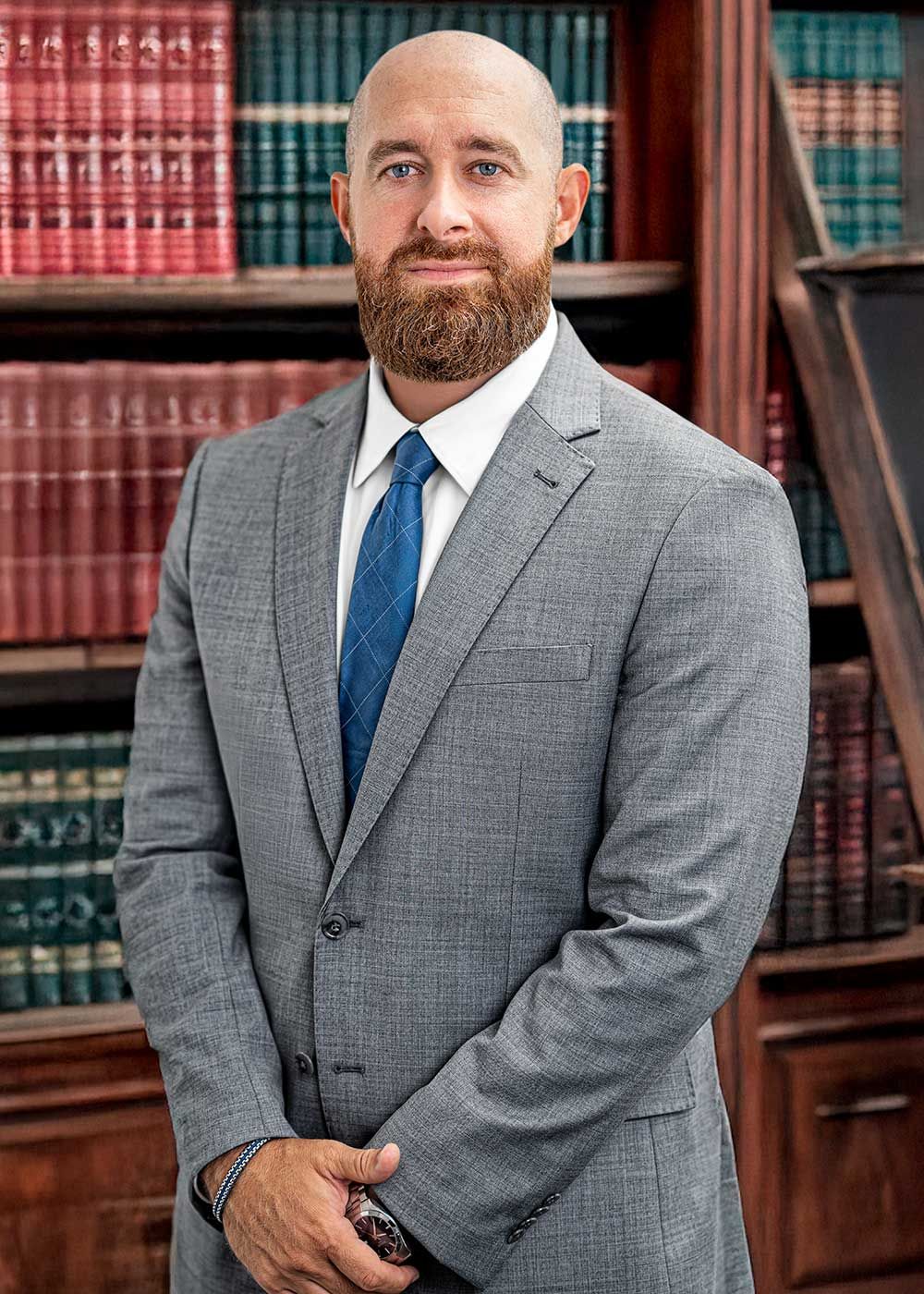 A man in a blue plaid suit is standing with his arms crossed.