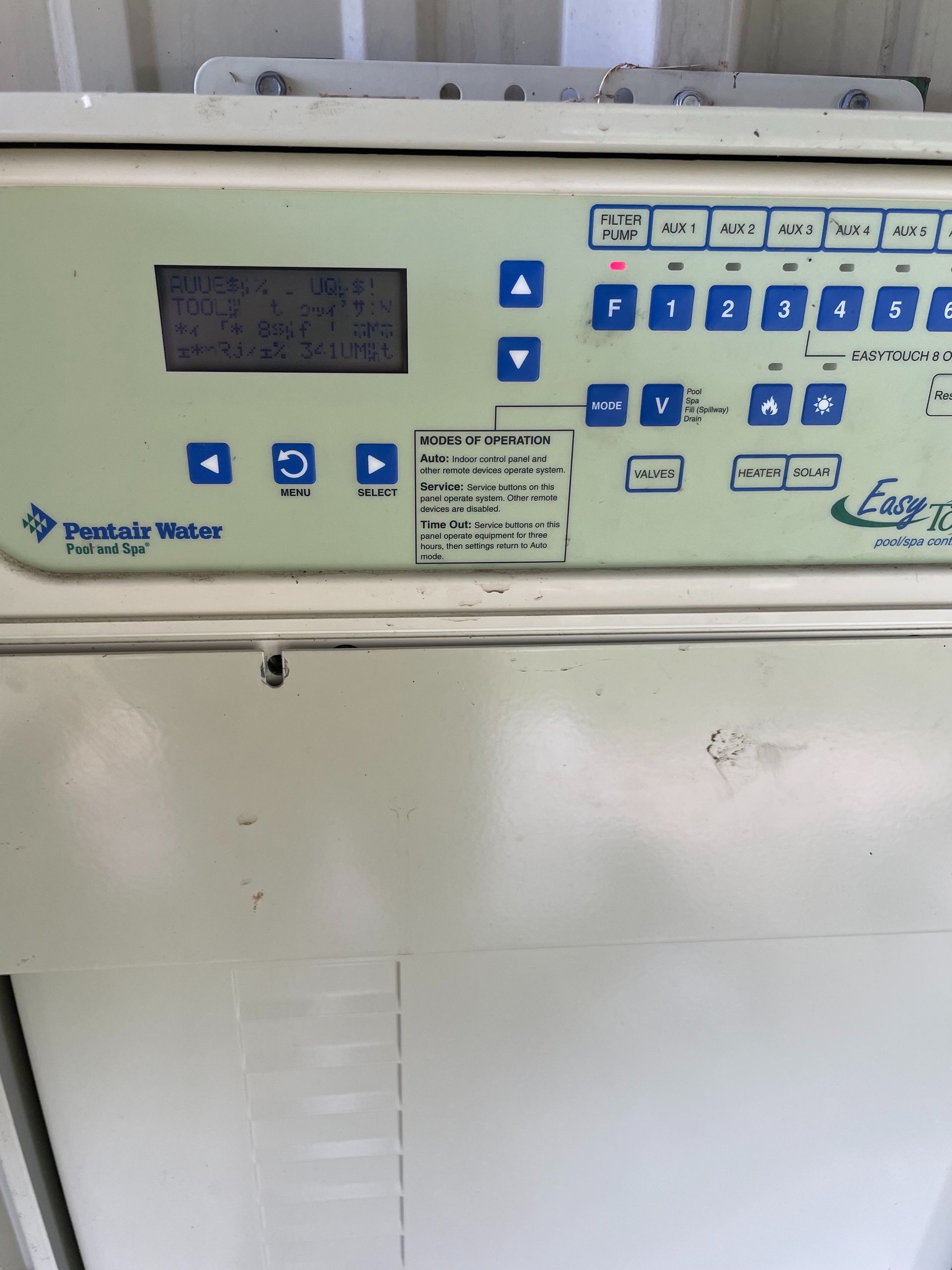 Wall-mounted control panel with buttons, display, and labels on a white machine in a lab or utility room