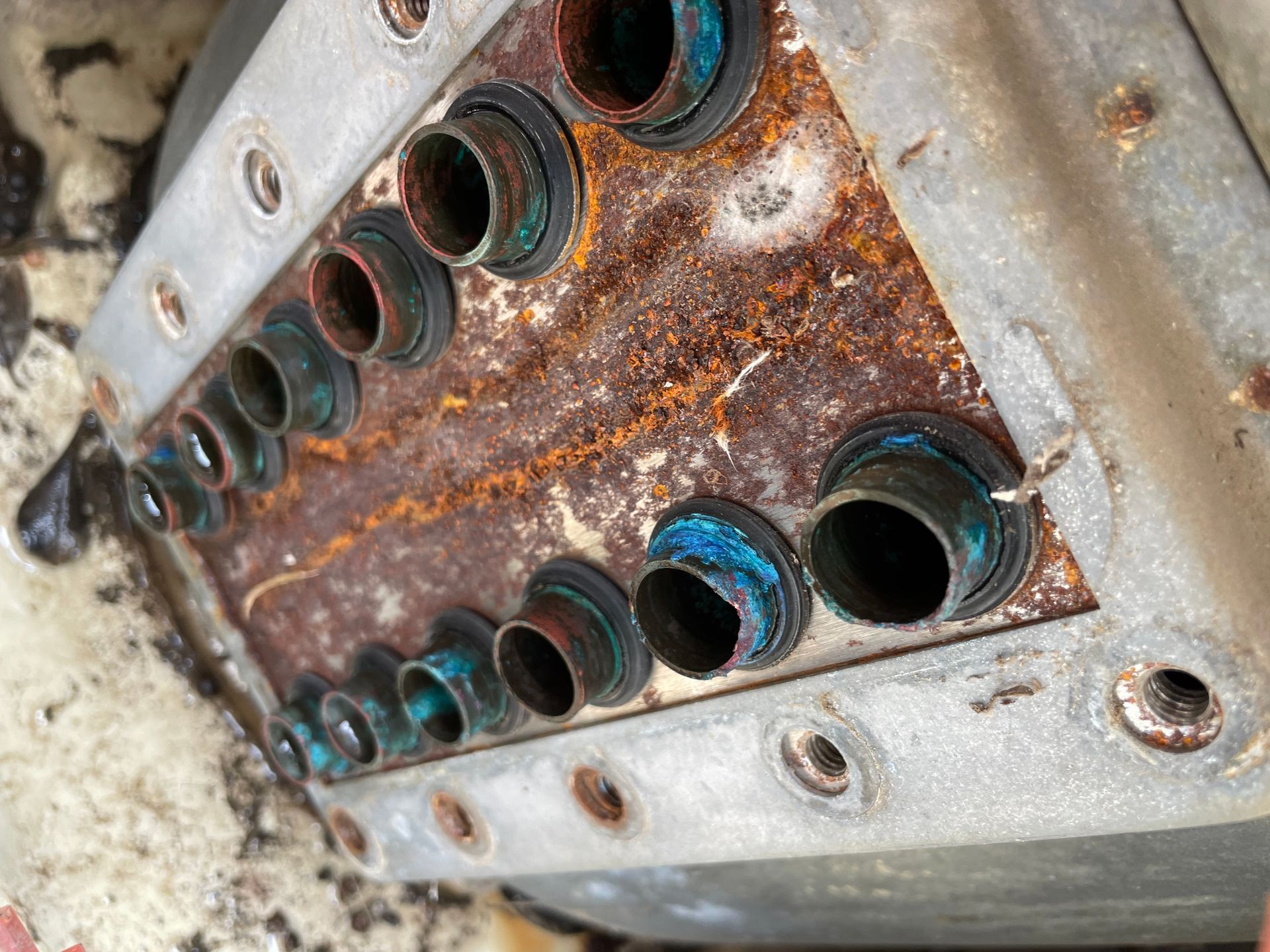 Rusty metal machine housing with rows of circular openings and blue gaskets close up