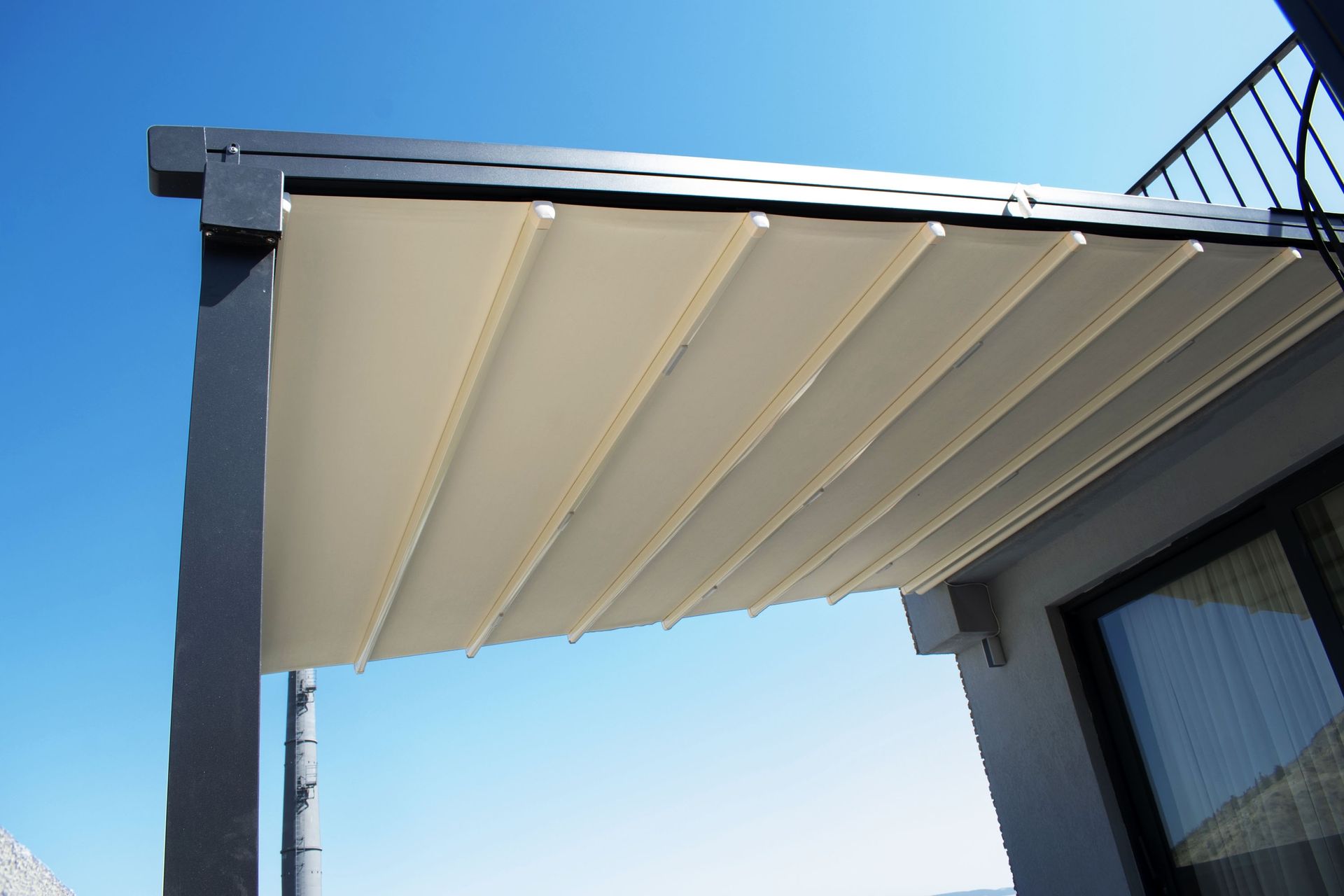 a white canopy is covering a balcony with a blue sky in the background