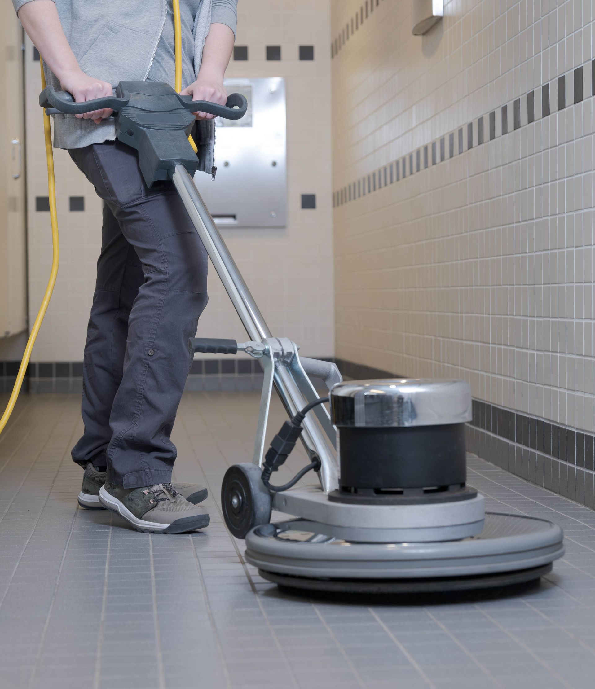 a person is using a machine to clean a tiled floor