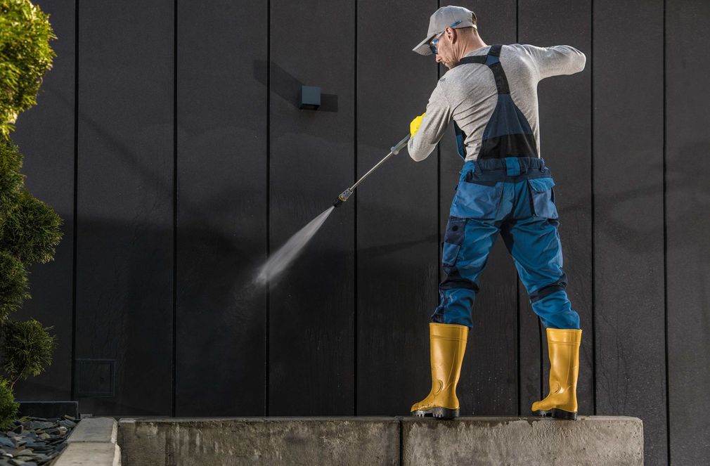a man is cleaning a wall with a high pressure washer