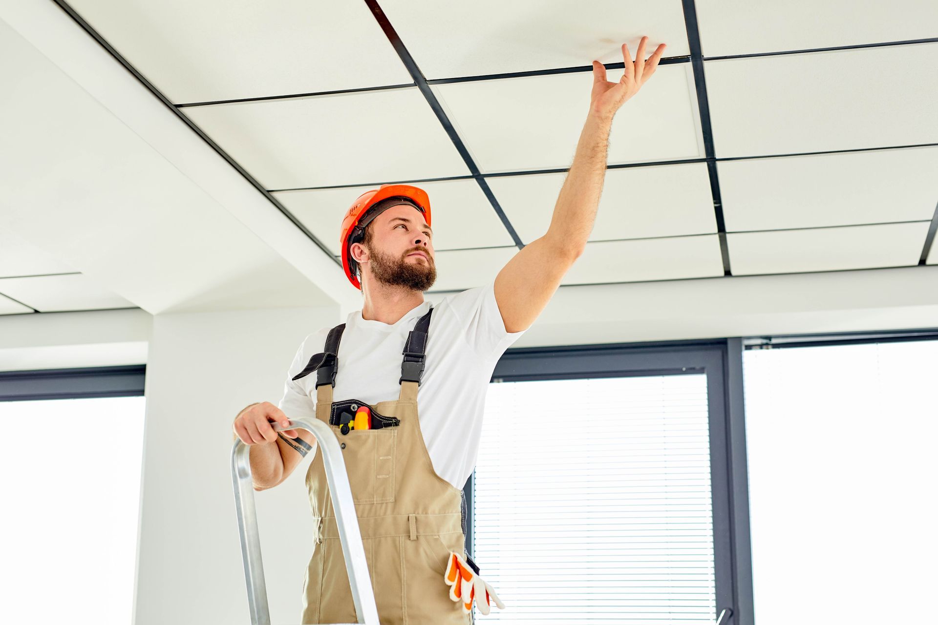 a man is standing on a ladder looking up at the ceiling