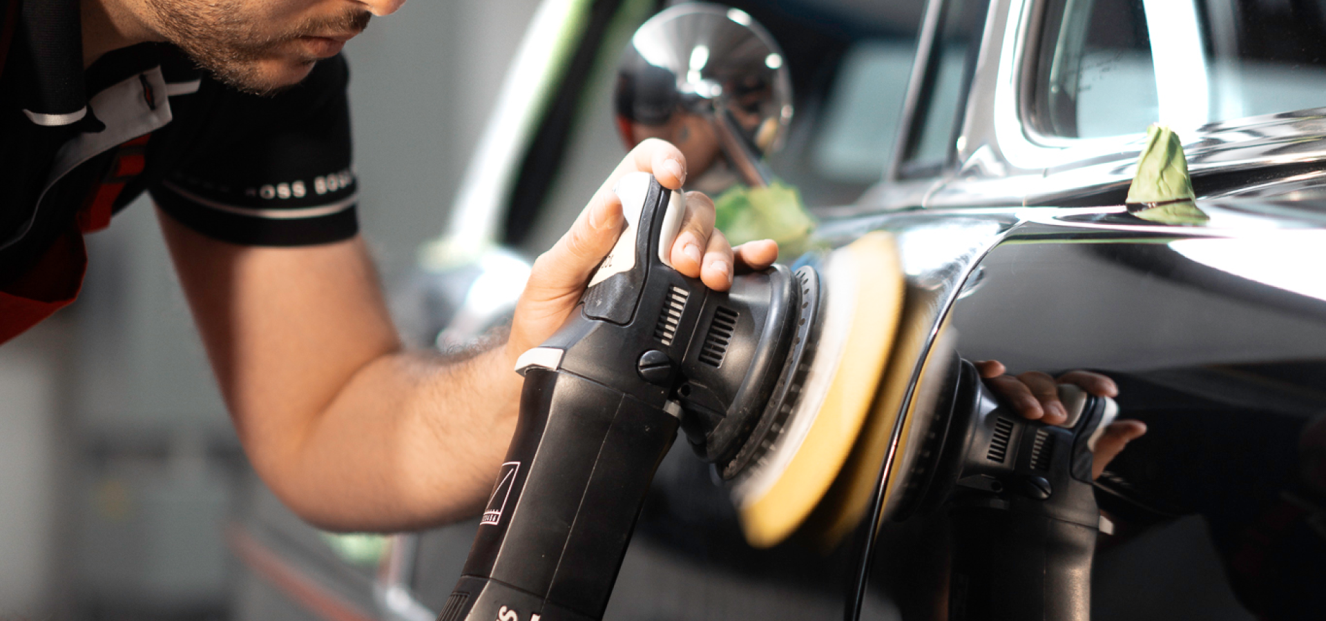 Detailing a black car with a rotary buffer and polish pad