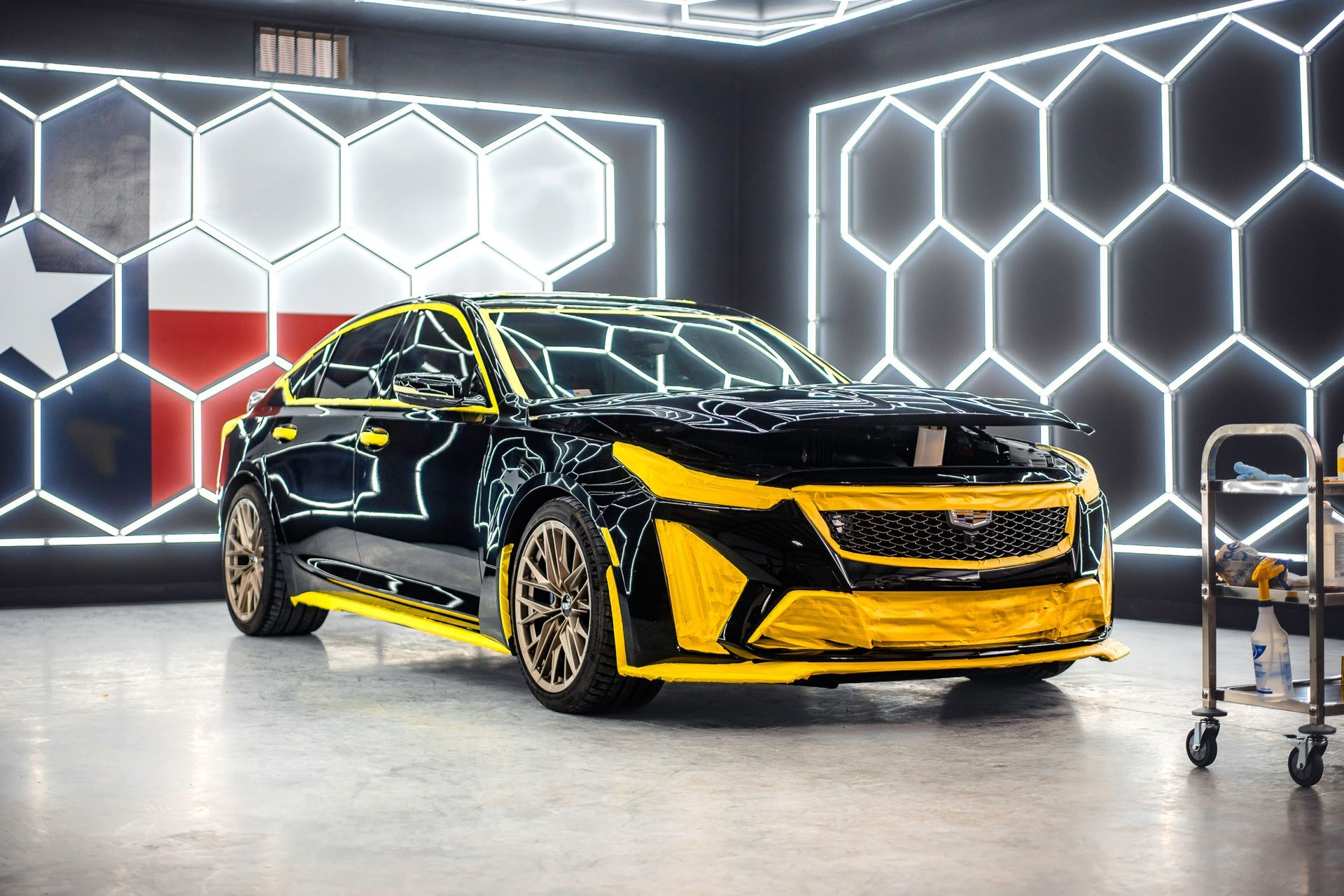Black-and-yellow sports sedan in a neon-lit garage with hexagonal wall lights
