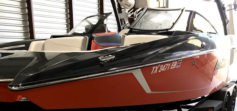 Red and black speedboat on display indoors with a windshield and white lettering on the side