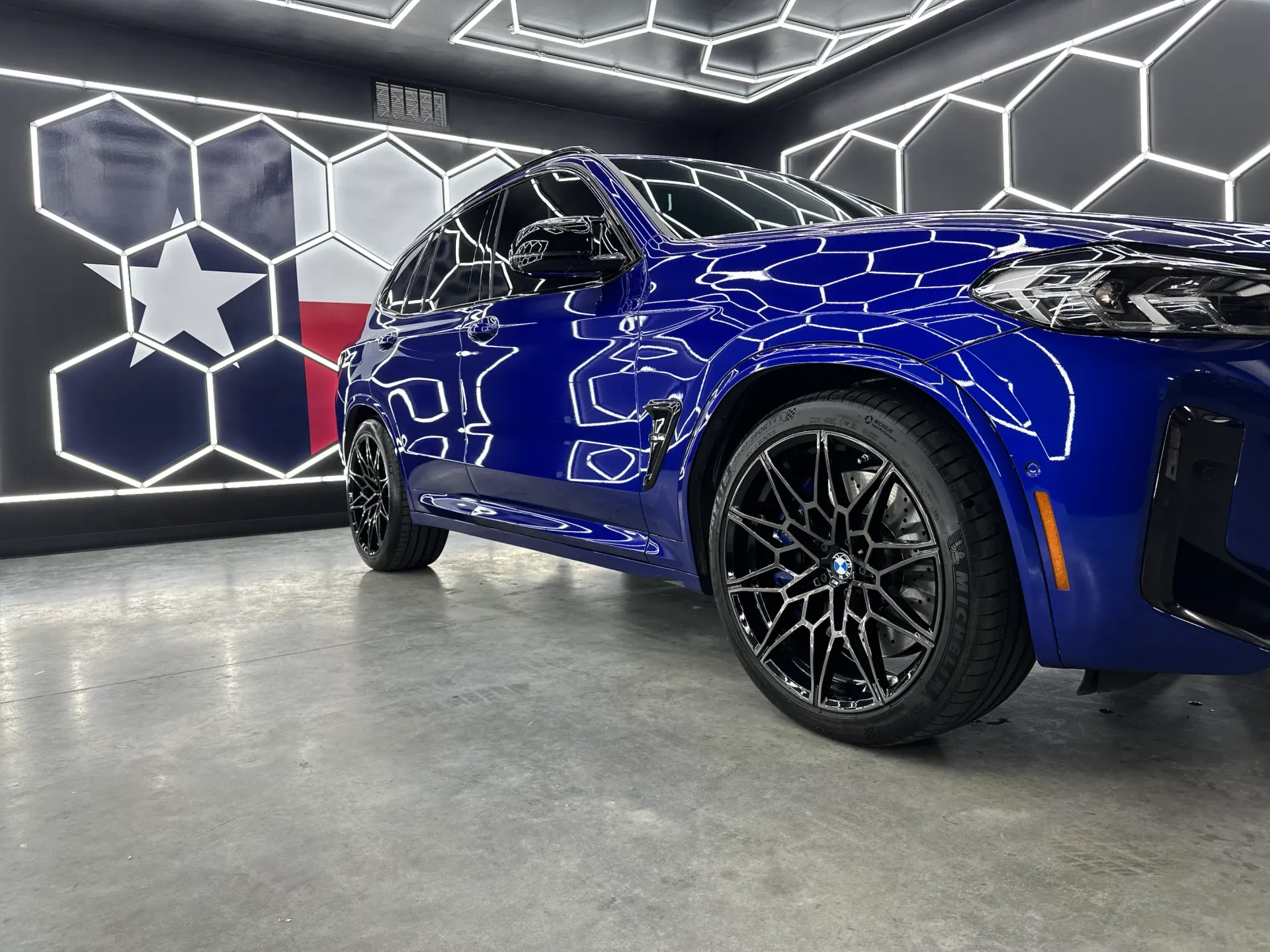 Blue sports car in a modern showroom with hexagonal wall art and polished concrete floor