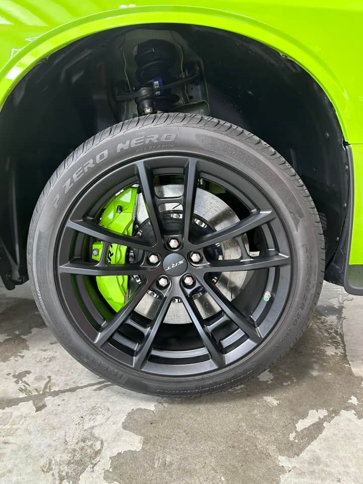 Black car wheel with neon green brake caliper under lime green fender