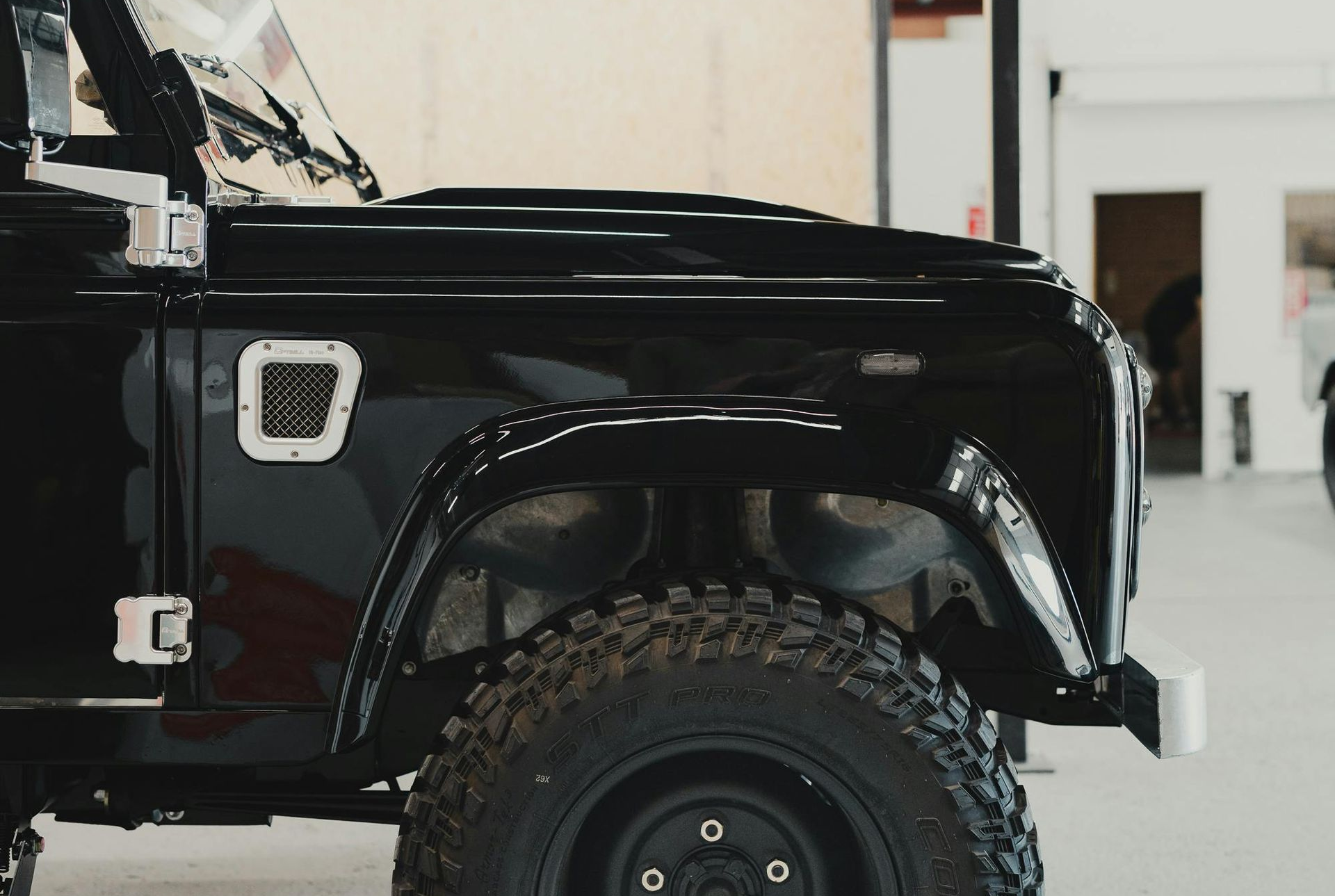 Black off-road SUV side view with large tires in a garage