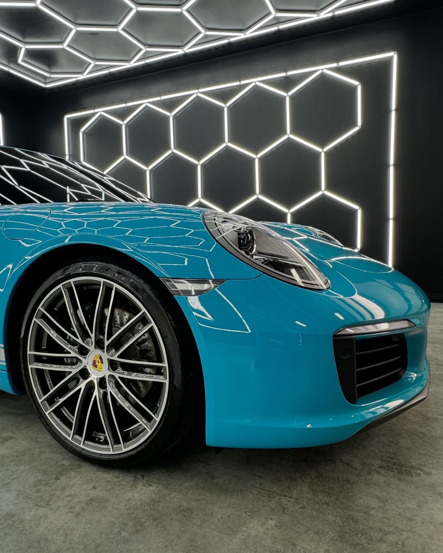 Blue sports car in a showroom with geometric hexagon LED wall lighting