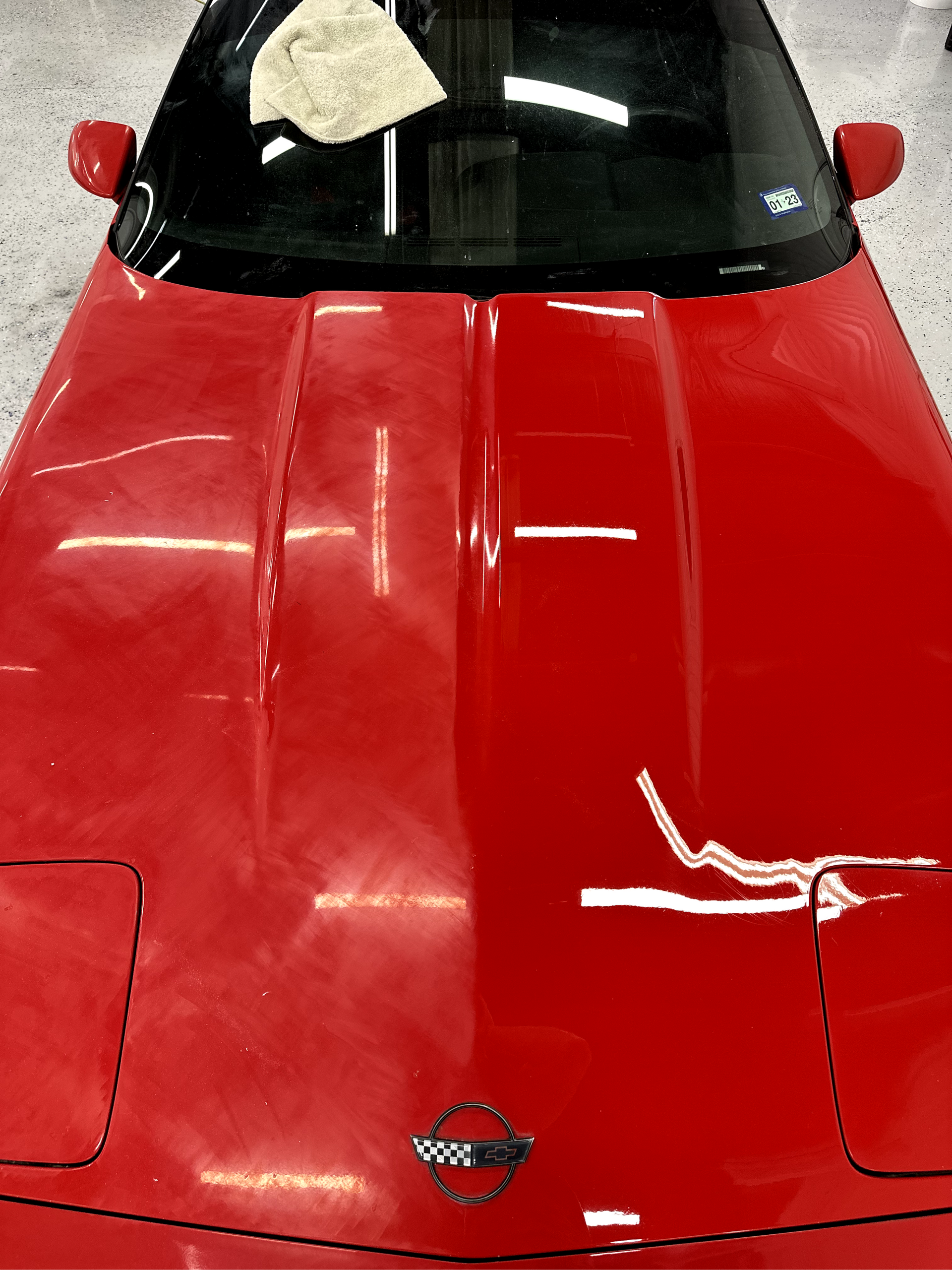A red corvette is parked in a garage.