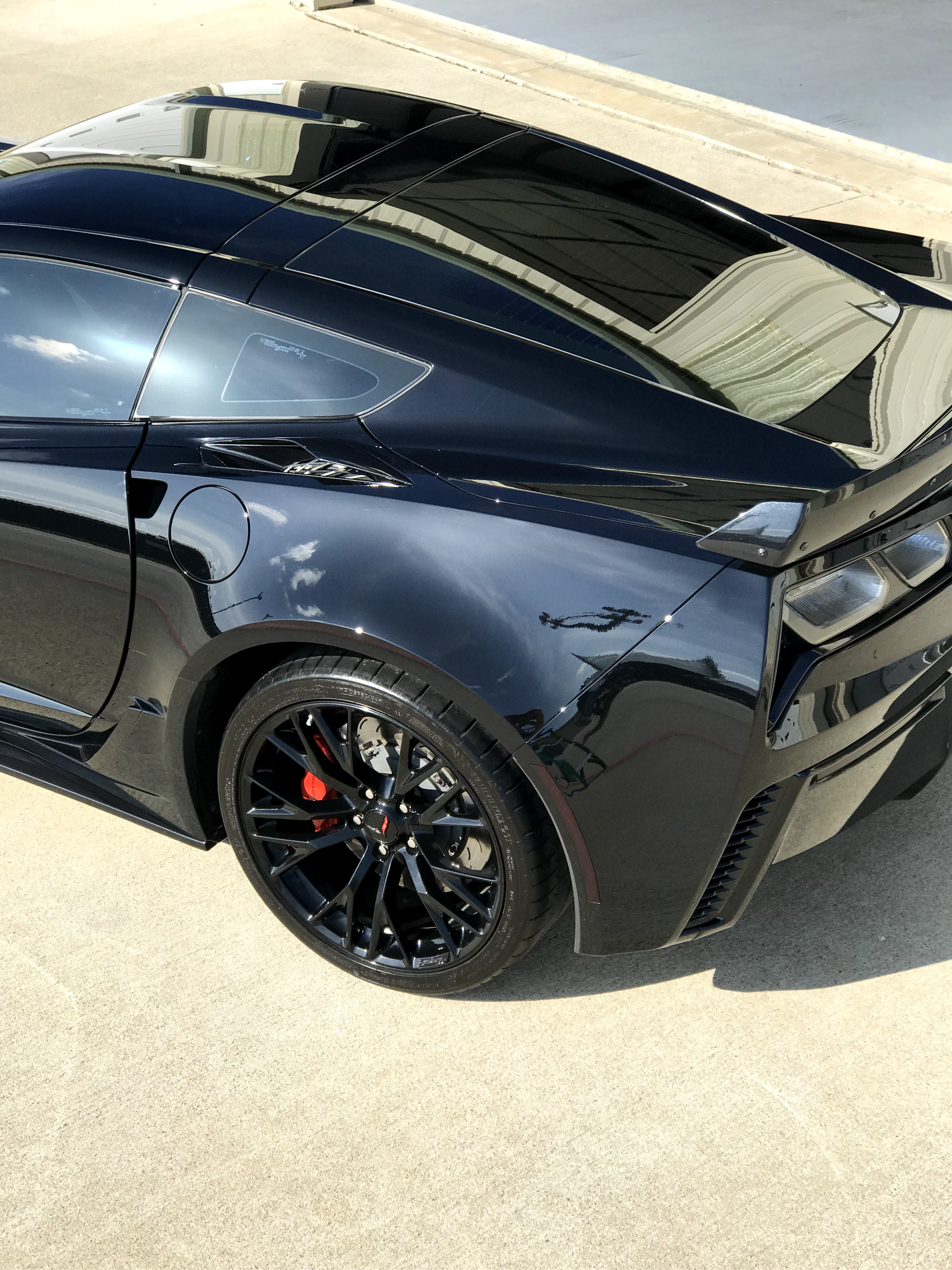 Black sports coupe with tinted windows, black rims, and red brake calipers parked on a driveway