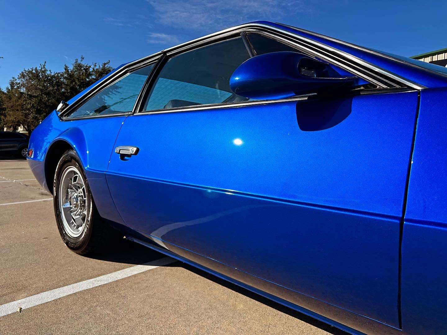 Blue sports car parked in a lot, side view in bright sunlight