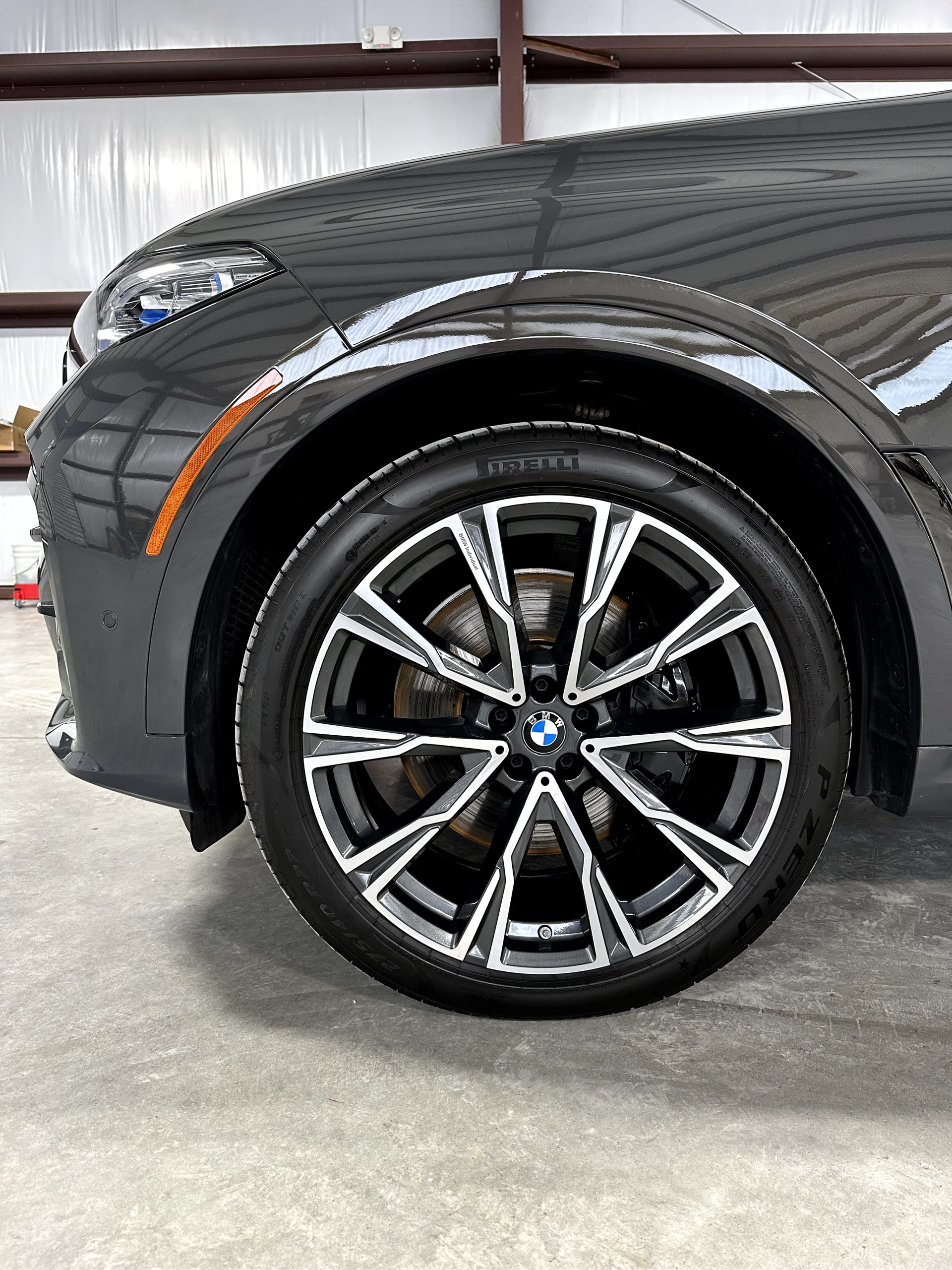 Close-up of a black BMW’s front wheel and fender in a garage.