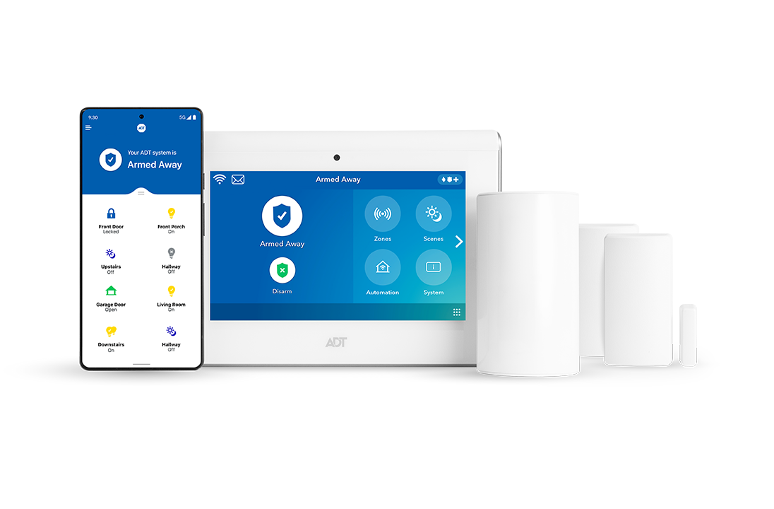 A security system is sitting on a table next to a tablet and a cell phone.
