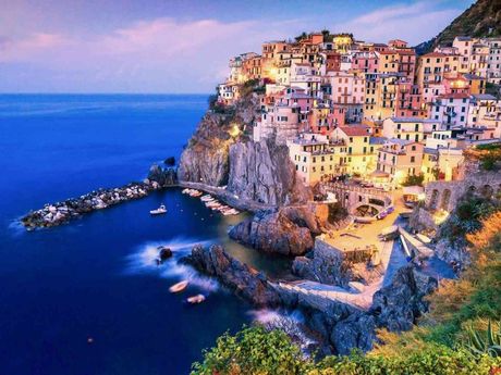 Colorful cliffside village overlooking a deep blue sea at sunset