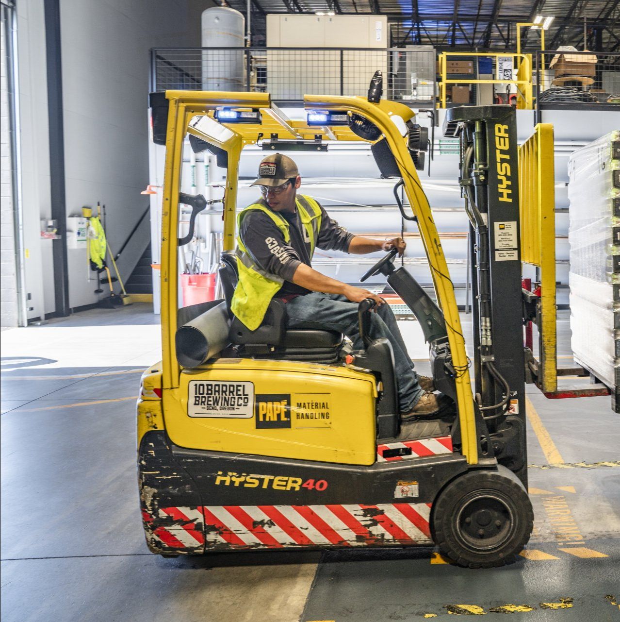A man is driving a yellow forklift in a warehouse