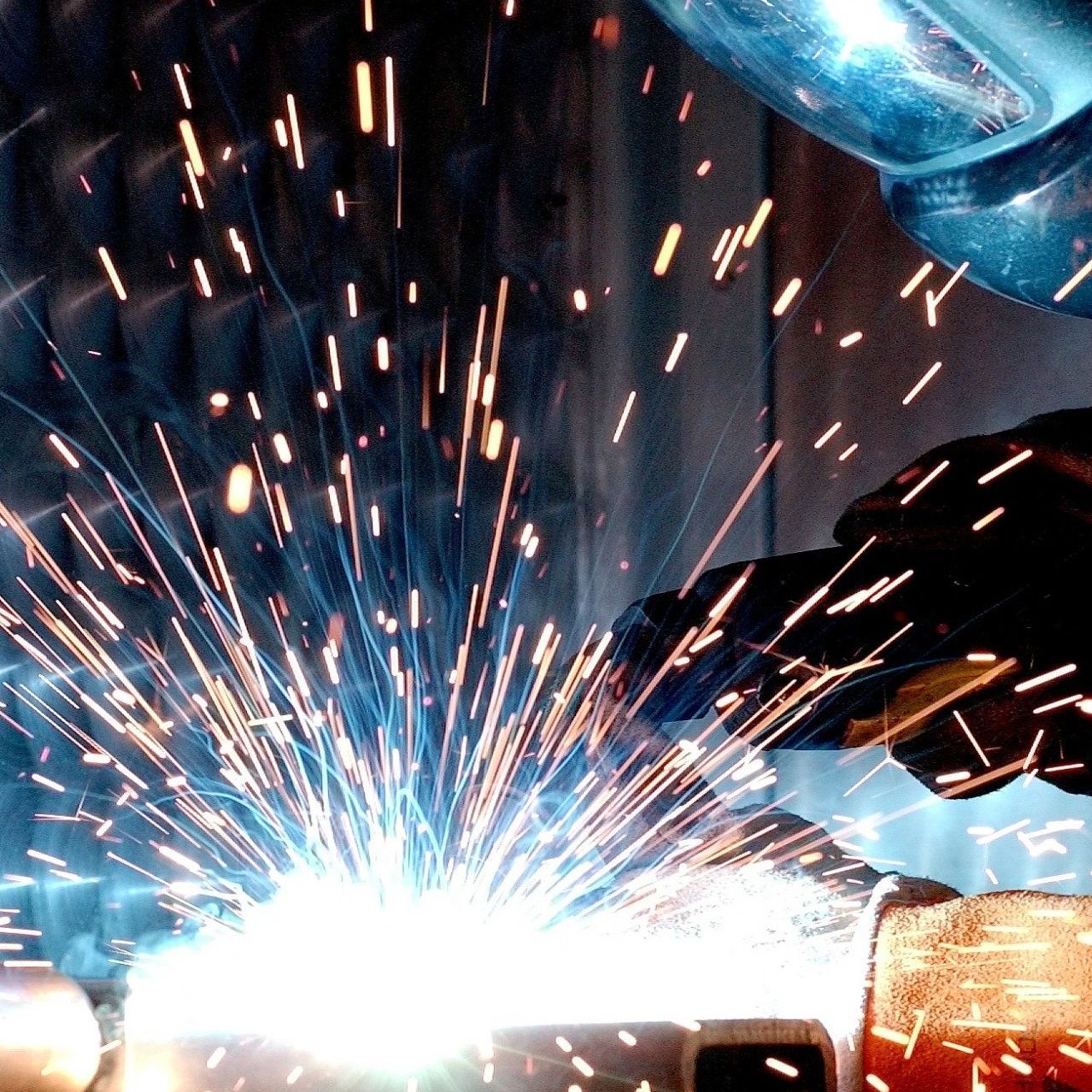 A person is welding a piece of metal with sparks coming out of it