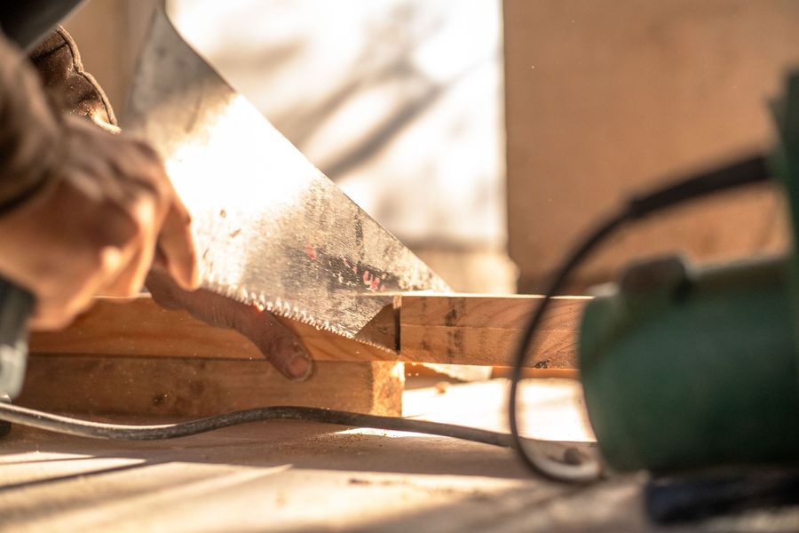 Hand sawing a wooden plank outdoors in warm sunlight