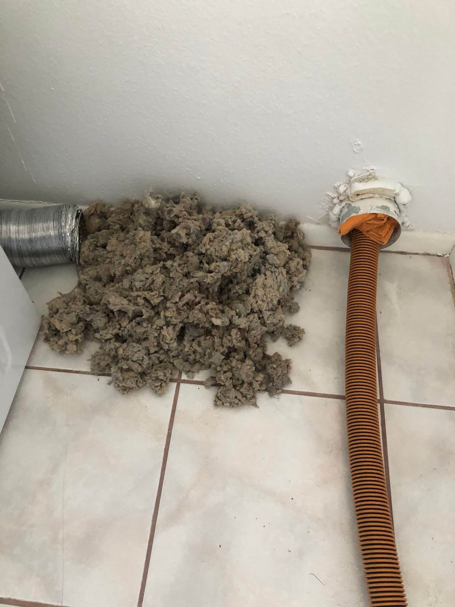 A bunch of dust is sitting on the floor next to a hose.