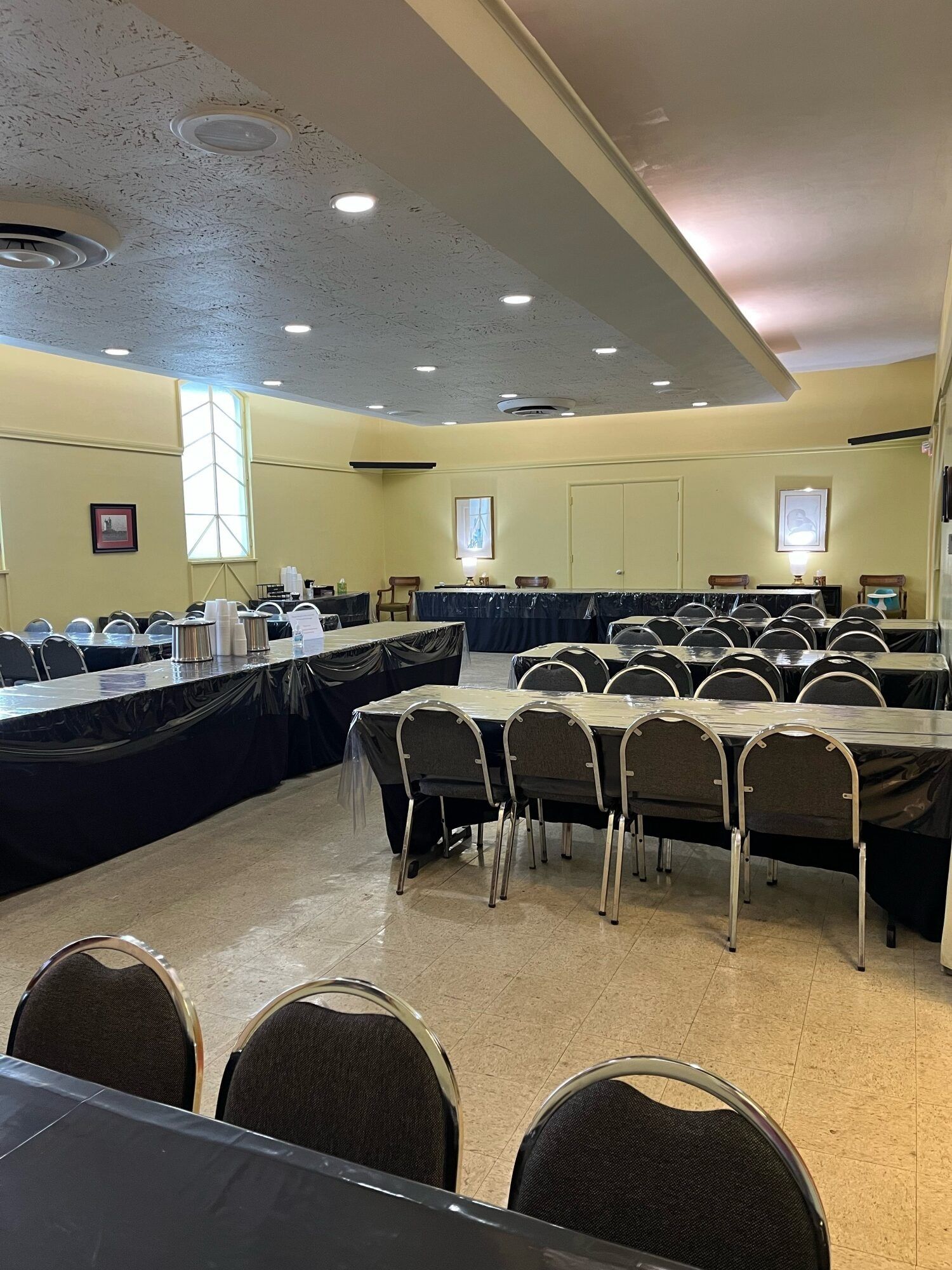 Empty banquet hall with rows of chairs, long tables, and a speaker area at the front