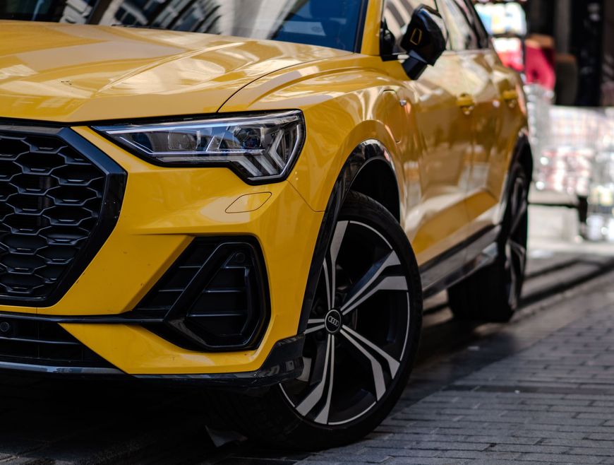 Auto sportiva rossa su sfondo nero, illuminata dal basso.