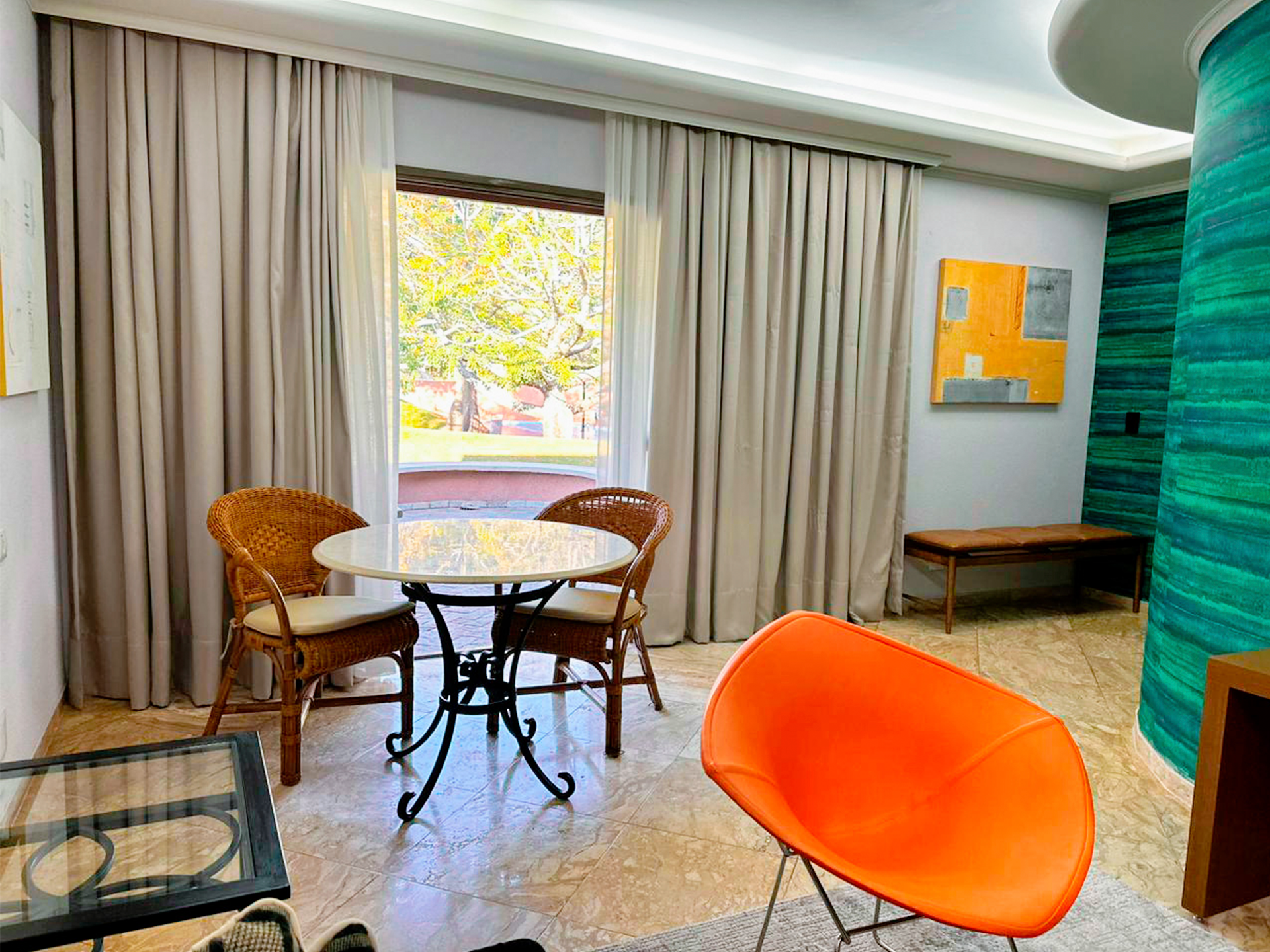 Uma sala de estar com mesa e cadeiras em frente a uma janela.