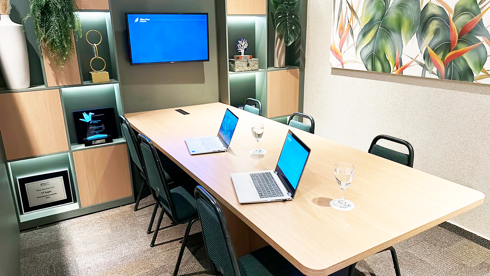 Uma sala de conferências com uma longa mesa e cadeiras e dois laptops.
