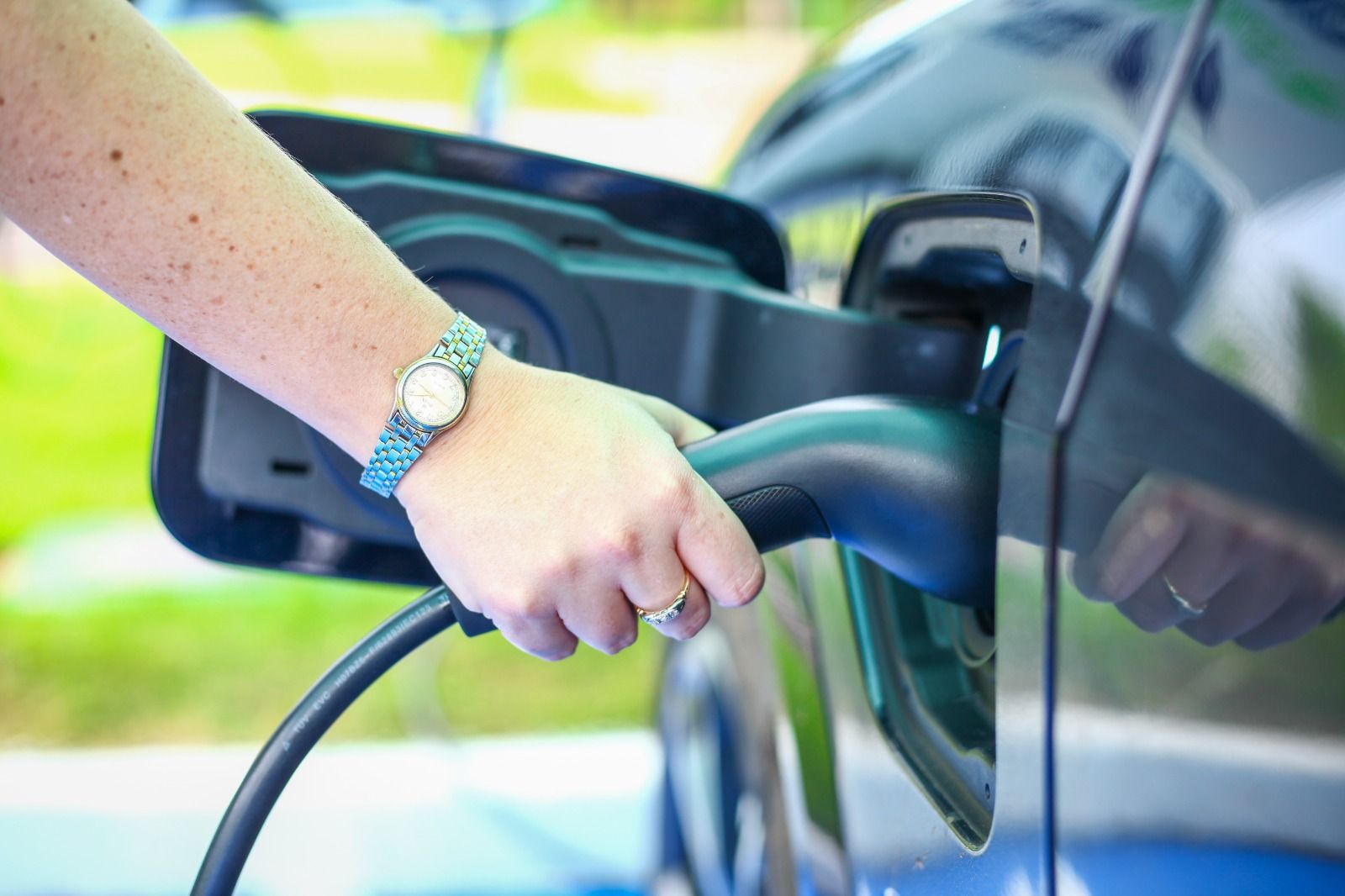 Uma mulher está carregando um carro elétrico em uma estação de carregamento.