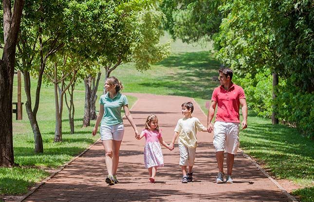 Uma família está andando de mãos dadas por um caminho em um parque.