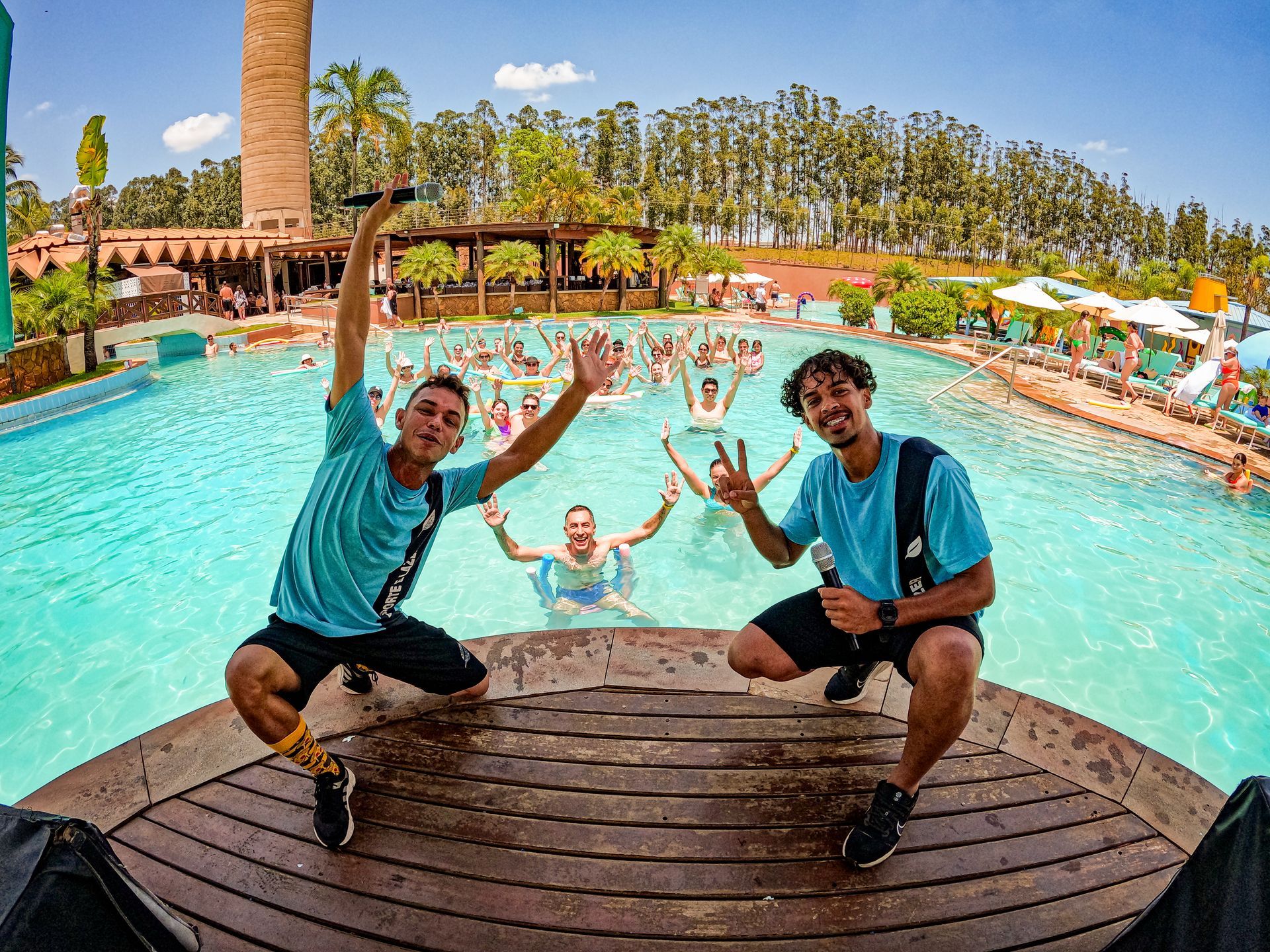 Dois homens estão posando para uma foto em frente a uma piscina.