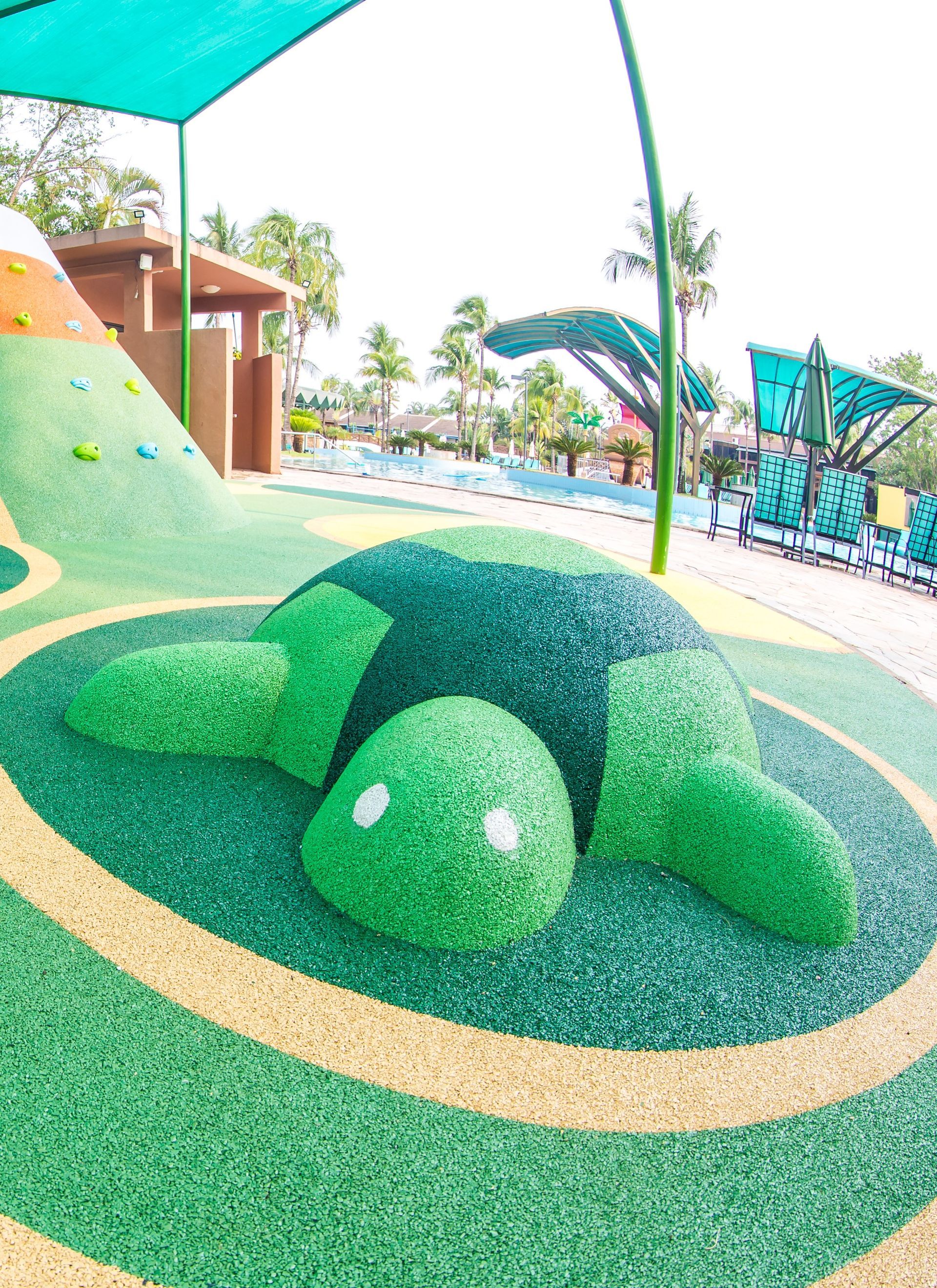 Uma tartaruga verde está deitada no chão em um playground.