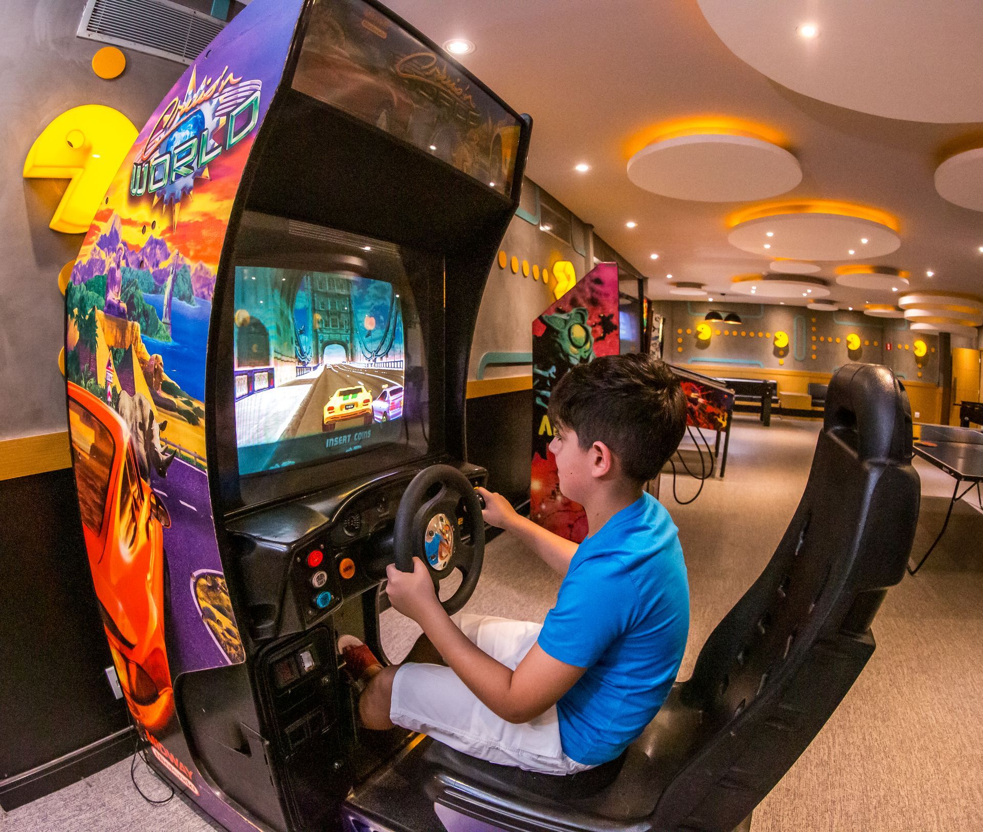 Um menino está jogando videogame em um fliperama.