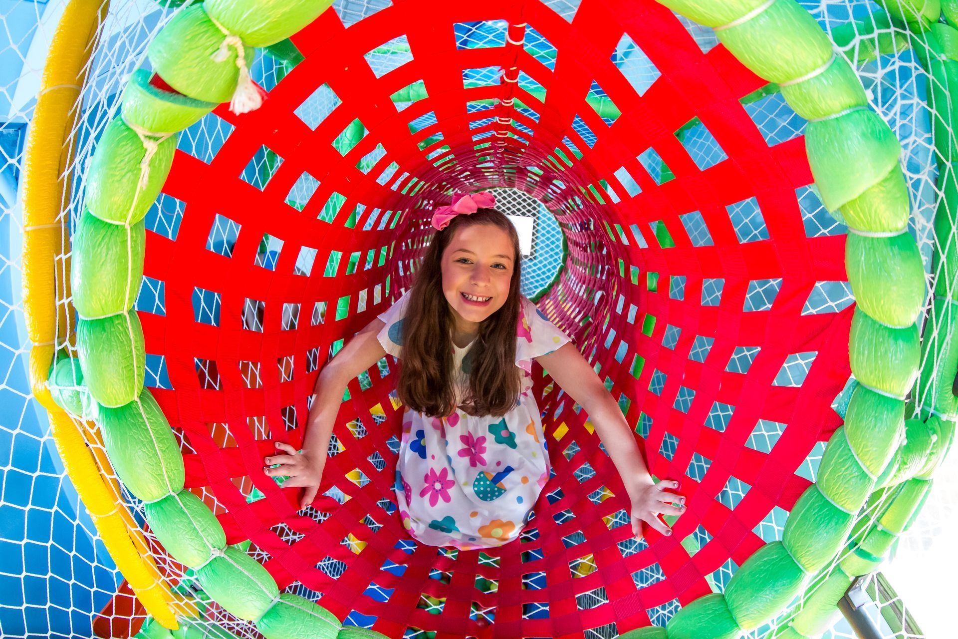 Uma garotinha está brincando em um túnel colorido.