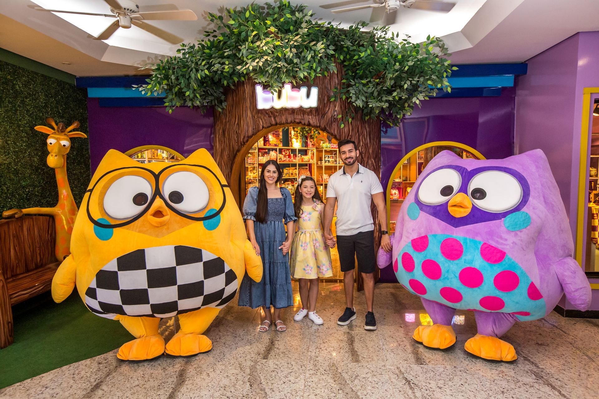 Uma família está em frente a uma loja com mascotes de coruja.