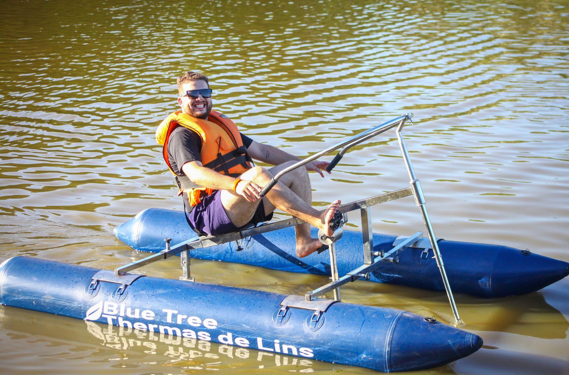 Um homem está sentado em uma jangada azul na água.