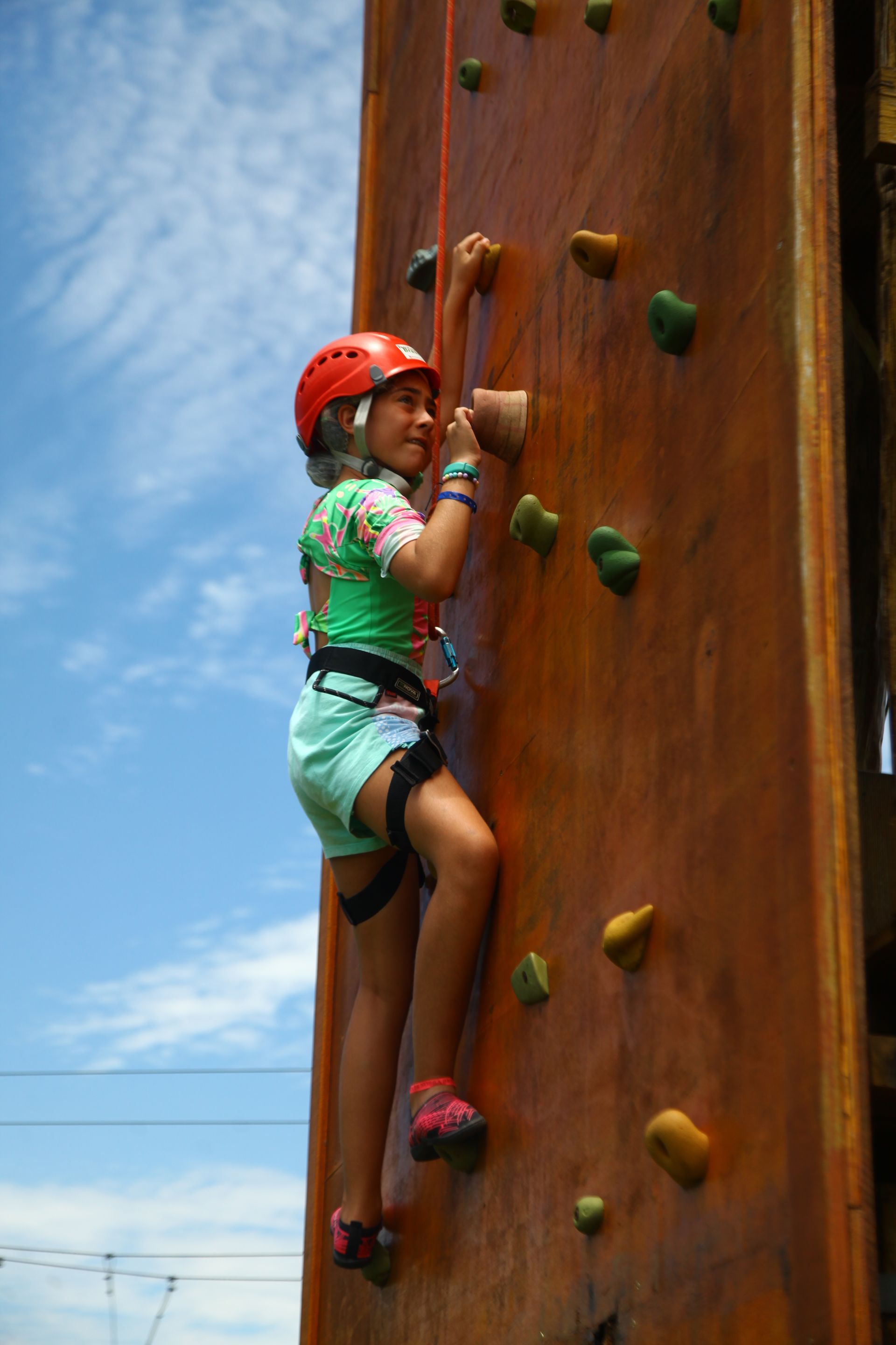 Uma jovem está escalando uma parede de escalada de madeira.