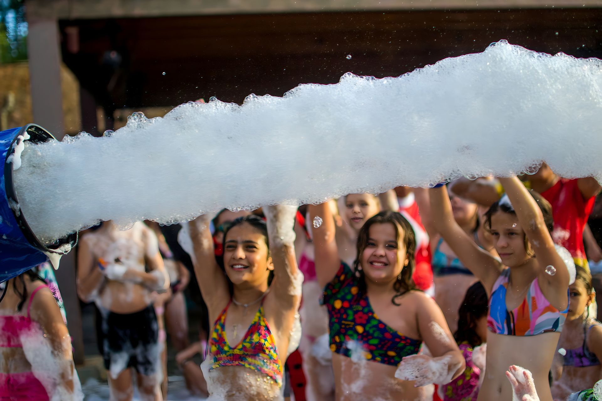 Um grupo de jovens garotas estão em frente a uma máquina de espuma.