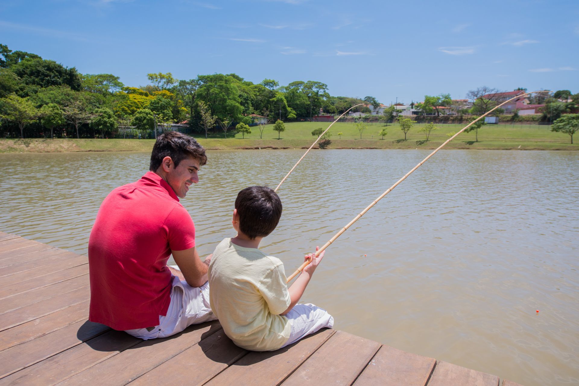 Um homem e um menino estão sentados em um cais pescando em um lago.