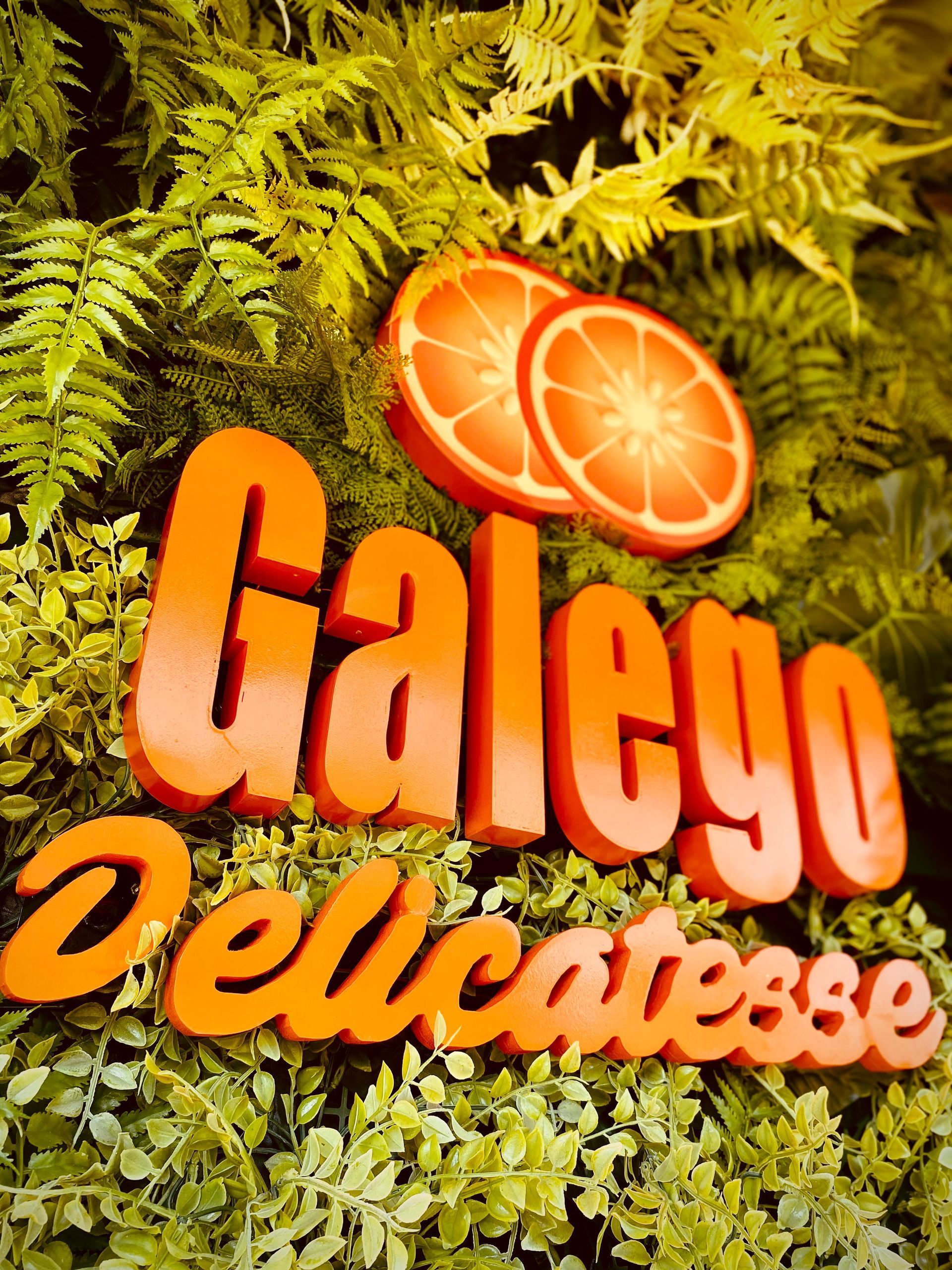 Uma placa para delicatessen galego é cercada por vegetação