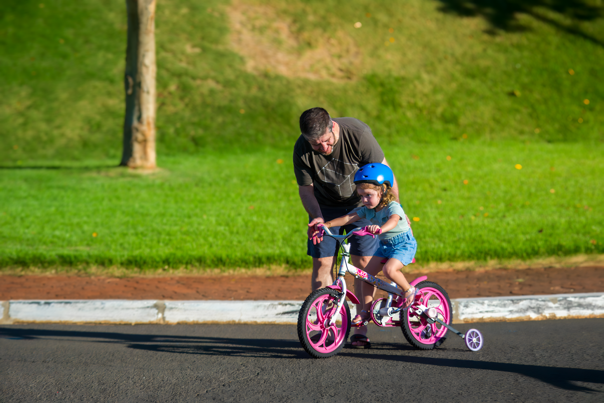 Um homem está ensinando uma menina a andar de bicicleta.
