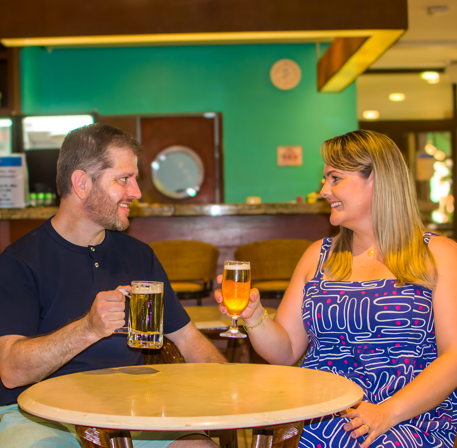 Um homem e uma mulher estão sentados à mesa bebendo cerveja