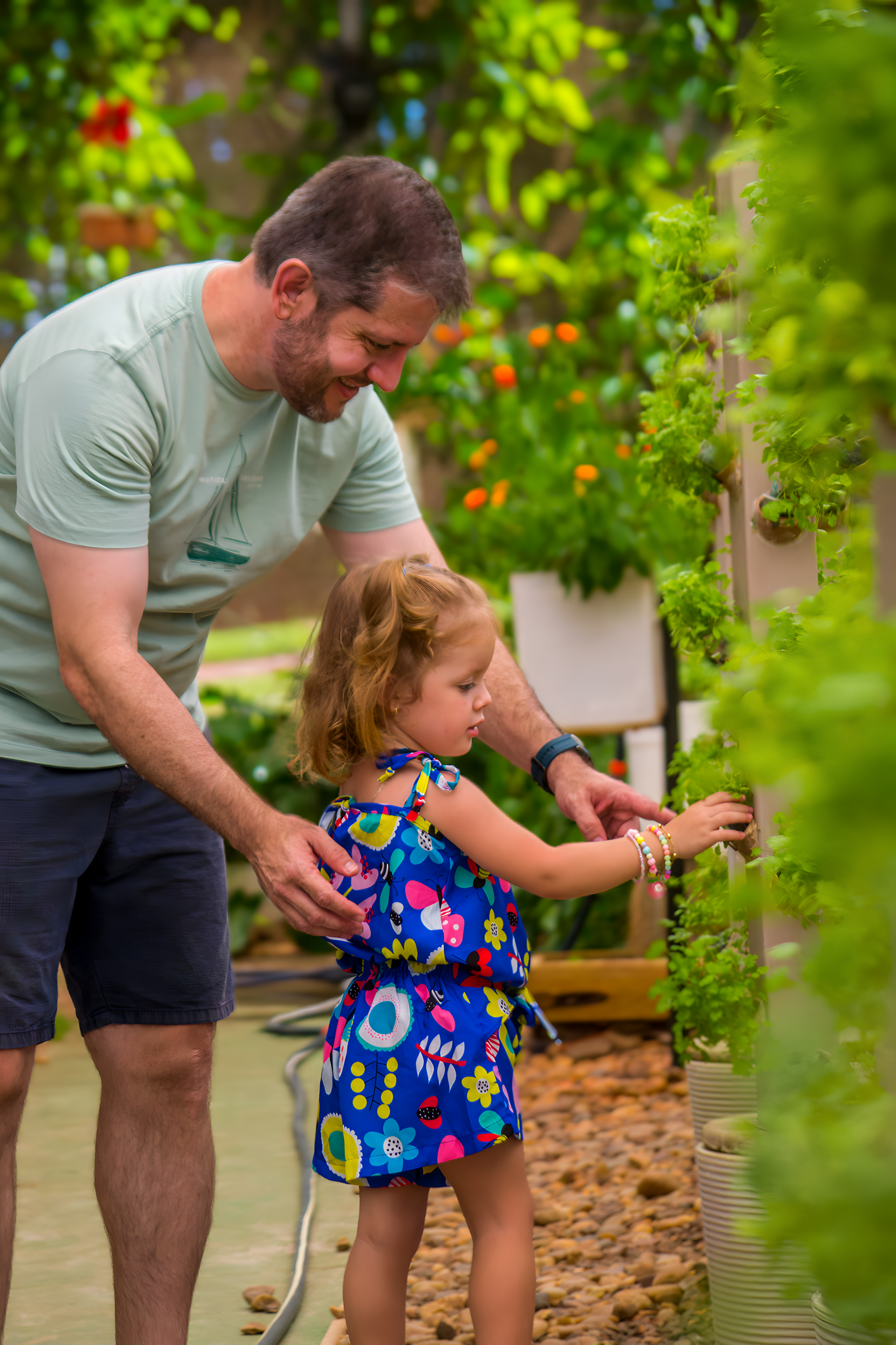 Um homem e uma menina regam plantas em um jardim.