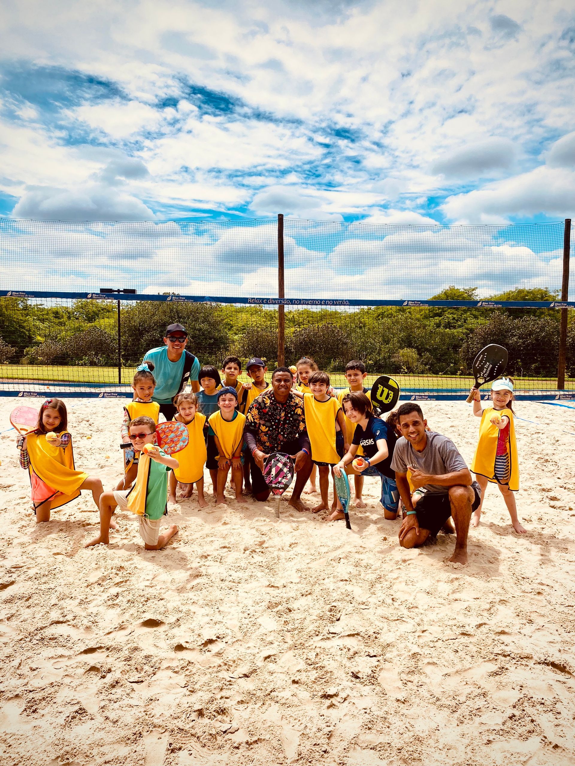 Um grupo de crianças está posando para uma foto em uma praia de areia.