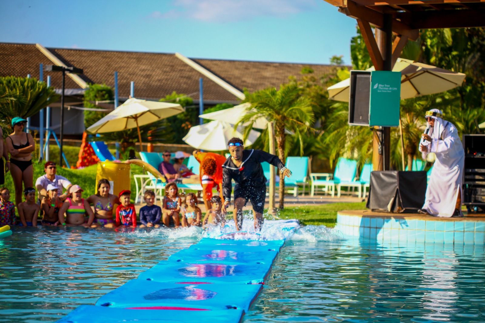 Um grupo de pessoas está em volta de uma piscina.